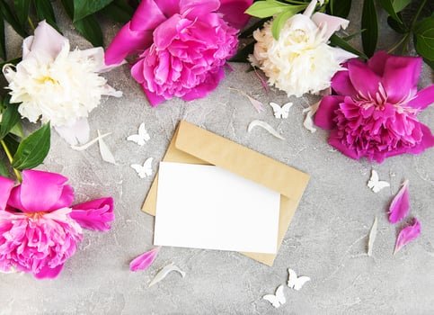 invitation card, craft envelope and pink peony flowers photo
