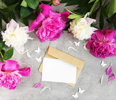 invitation card, craft envelope and pink peony flowers photo