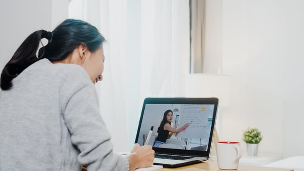 Young Asia teen girl university student using laptop computer distance learn lesson with female teacher remote teaching on internet at home. Social distancing, quarantine for corona virus prevention. photo