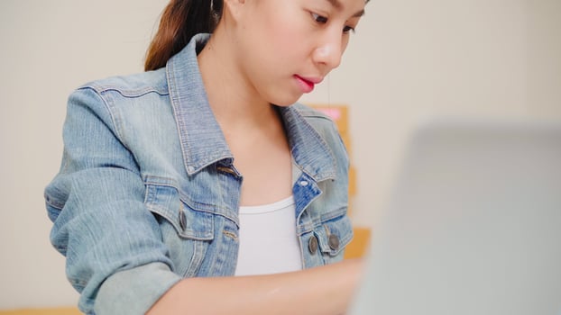 Beautiful smart Asian young entrepreneur business woman owner of SME online checking product on stock and save to computer working at home. Small business owner at home office concept. photo