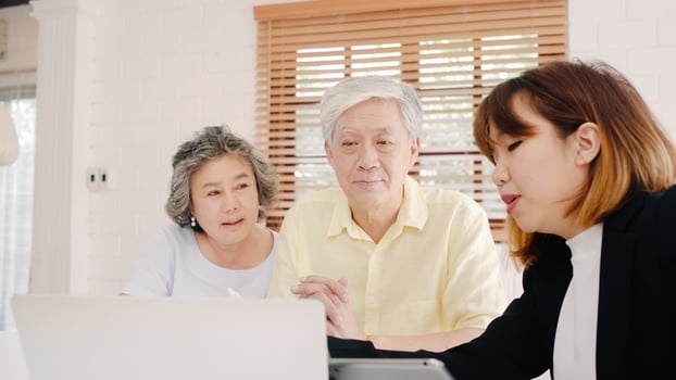 Asia smart female agent offers health insurance for elderly couples by document, tablet and laptop. Aged Asian couple consulting with insurance agent while sitting together with at home. photo