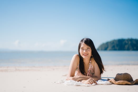 Beautiful Young Asian woman lying on beach happy relax near sea. Lifestyle women travel on beach concept. photo