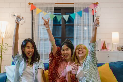Group of Asian women party at home, female drinking cocktail talking having funny together on sofa in living room in night. Teenager young friend play game, friendship, celebrate holiday concept. photo