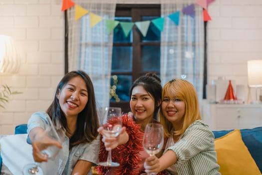 Group of Asian women party at home, female drinking cocktail talking having funny together on sofa in living room in night. Teenager young friend play game, friendship, celebrate holiday concept. photo