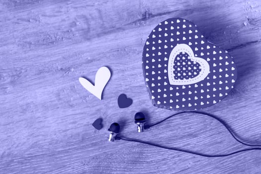 Headphones and a gift box in the shape of a heart and small hearts on a very peri background. Music gift concept. Top view copy space photo