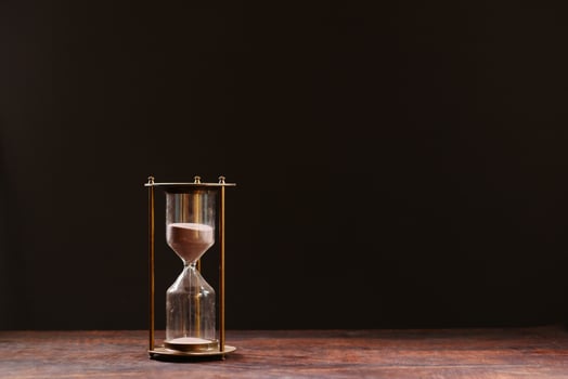 hourglass on table, sand flowing through the bulb of sandglass photo