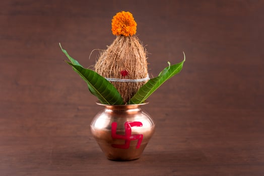 Copper kalash with coconut and mango leaf with floral decoration on a wooden background. essential in hindu puja. photo