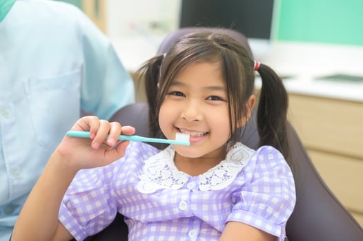 Female dentist demonstrating how to brush teeth to a little girl in dental clinic, teeth check-up and Healthy teeth concept photo