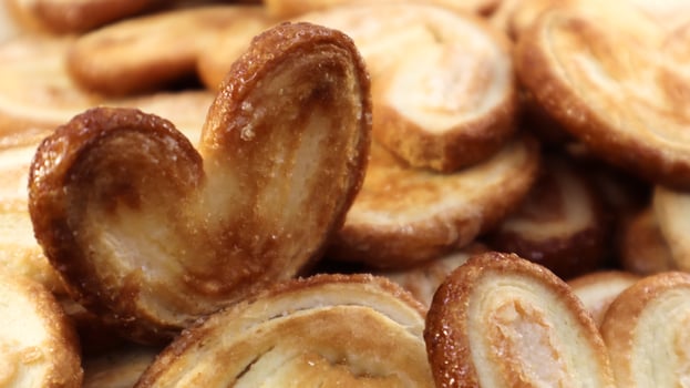 Fresh puff pastry palm cookies in the shape of a heart. Classic French pastries. Pig ear, elephant ear cookies, French hearts. photo