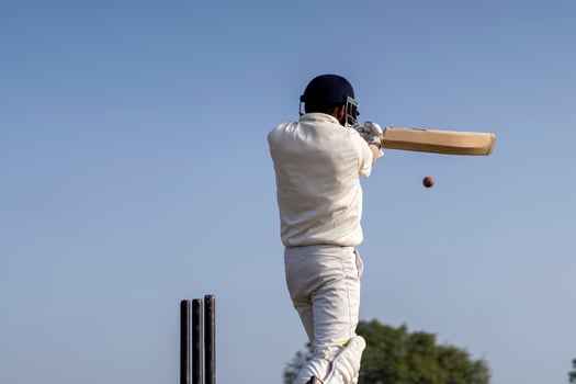 A cricketer playing cricket on the pitch in white dress for test matches. Sportsperson hitting a shot on the cricket ball. photo