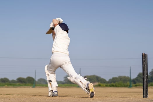 A cricketer playing cricket on the pitch in white dress for test matches. Sportsperson hitting a shot on the cricket ball. photo