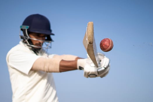 A cricketer playing cricket on the pitch in white dress for test matches. Sportsperson hitting a shot on the cricket ball. photo