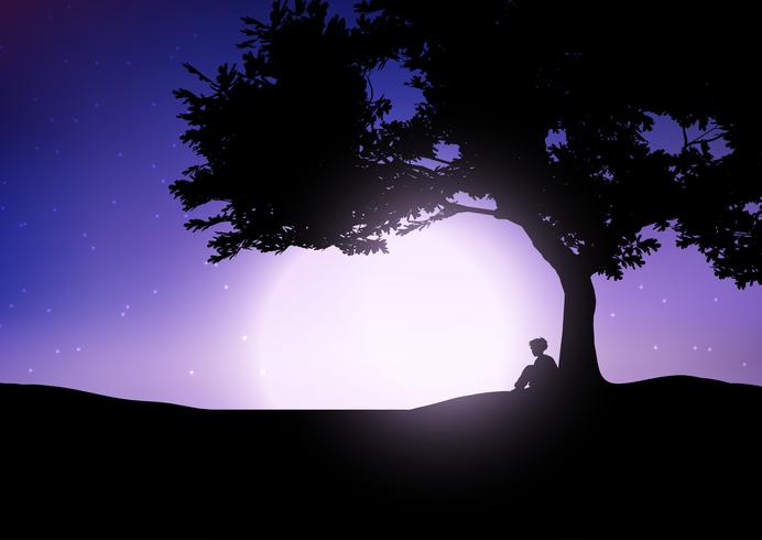 Boy sitting against a tree against a night sky