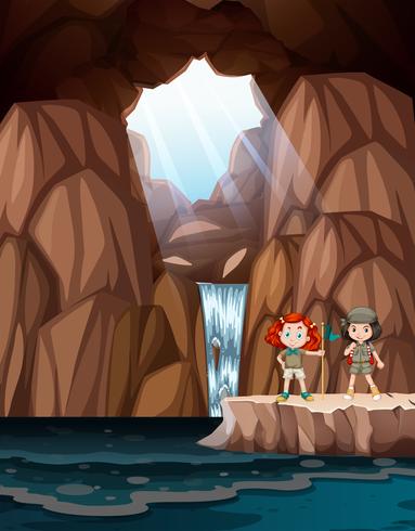 Girls exploring a cave with waterfall vector