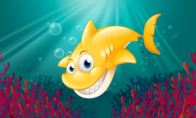 Un tiburón amarillo sonriendo bajo el mar vector