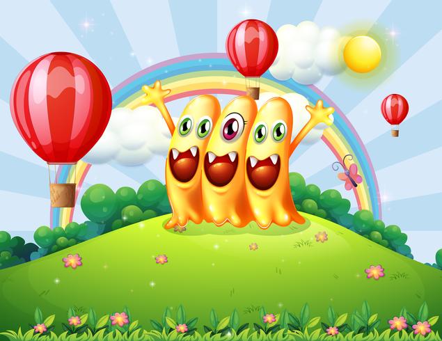 Una colina con tres monstruos felices observando los globos flotantes. vector