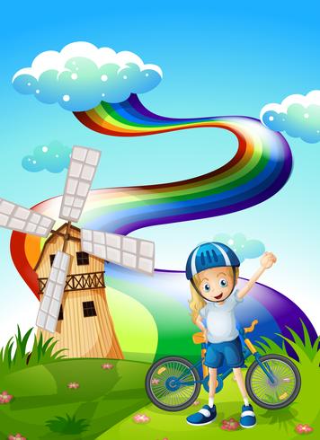 A young biker at the hilltop with a windmill and a rainbow vector