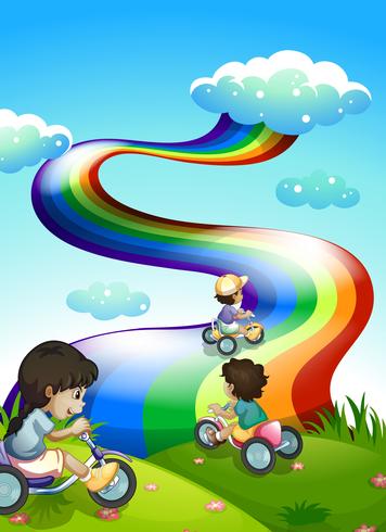 Niños jugando en la cima de la colina con un arco iris en el cielo vector