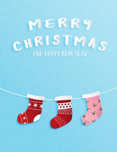 Christmas celebration and happy new year greeting or invitation card in paper cut style with Hanging Christmas socks decoration on blue background. vector