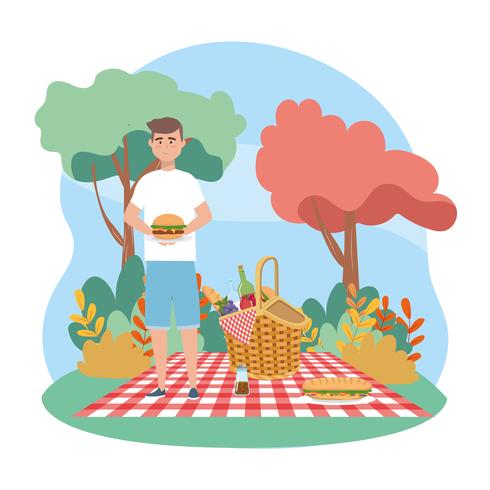 Hombre sujetando sandwich en manta de picnic vector