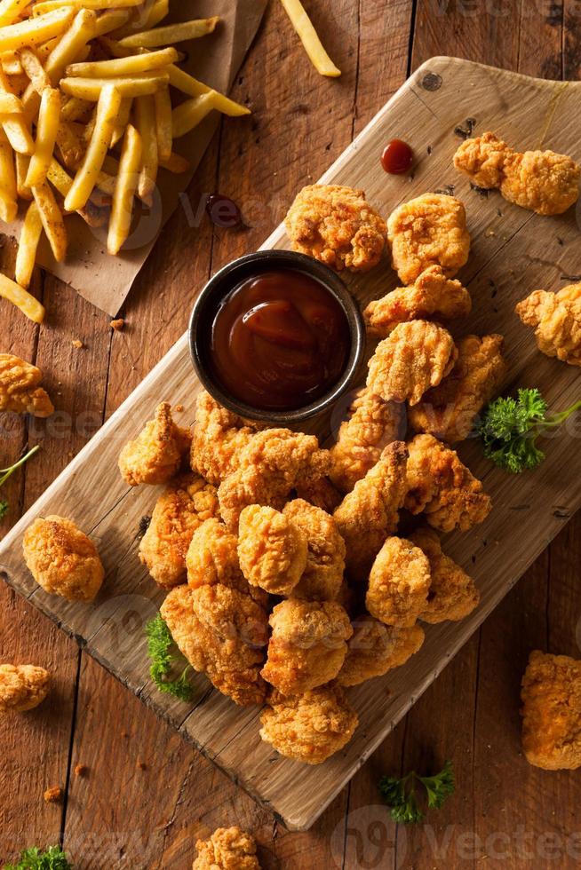 Crispy popcorn chicken and fries on a wood board photo