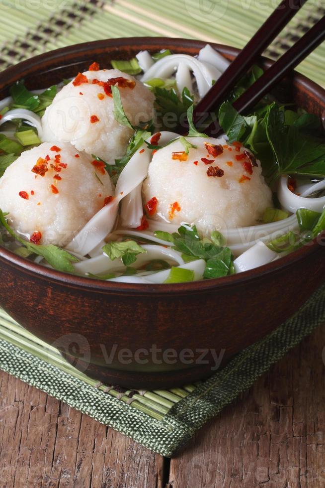 Sopa de fideos de arroz con bolas de pescado en un tazón de cerca. vertical foto