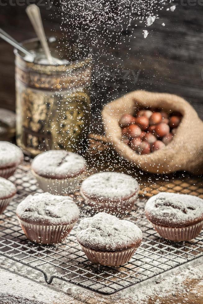 Falling icing sugar on fresh chocolate muffins photo