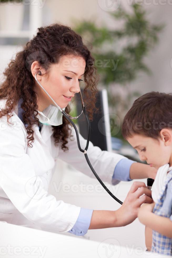 female doctor examines the boy with stethoscope photo