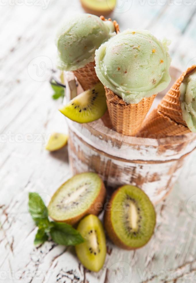 Kiwi fresh ice cream scoops in cones on wood photo