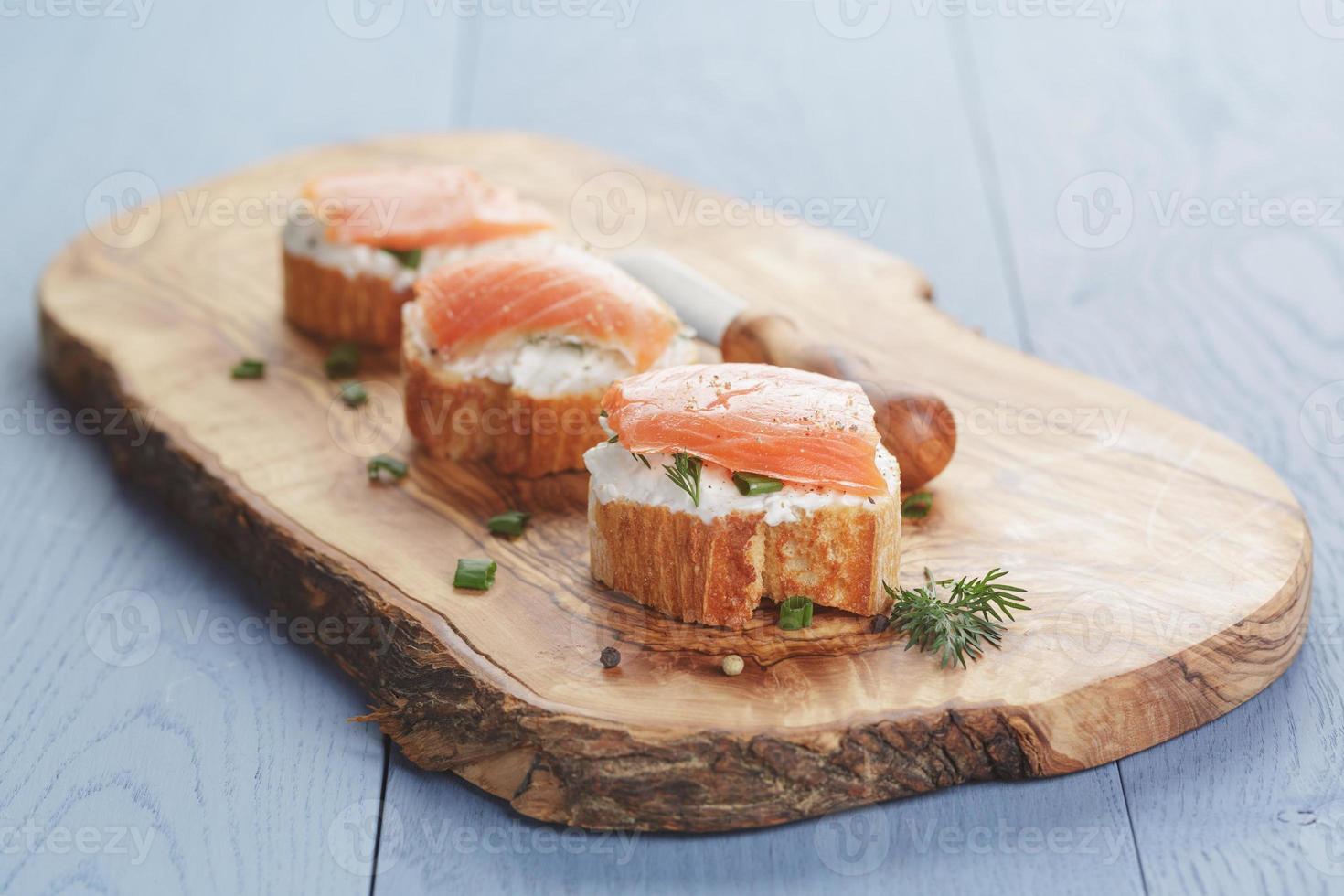 pequeños sándwiches con queso suave y salmón en mesa de madera foto