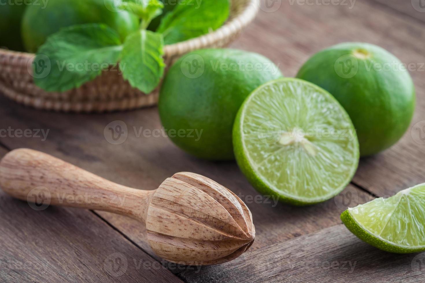 Wooden squeezer and lime on table photo