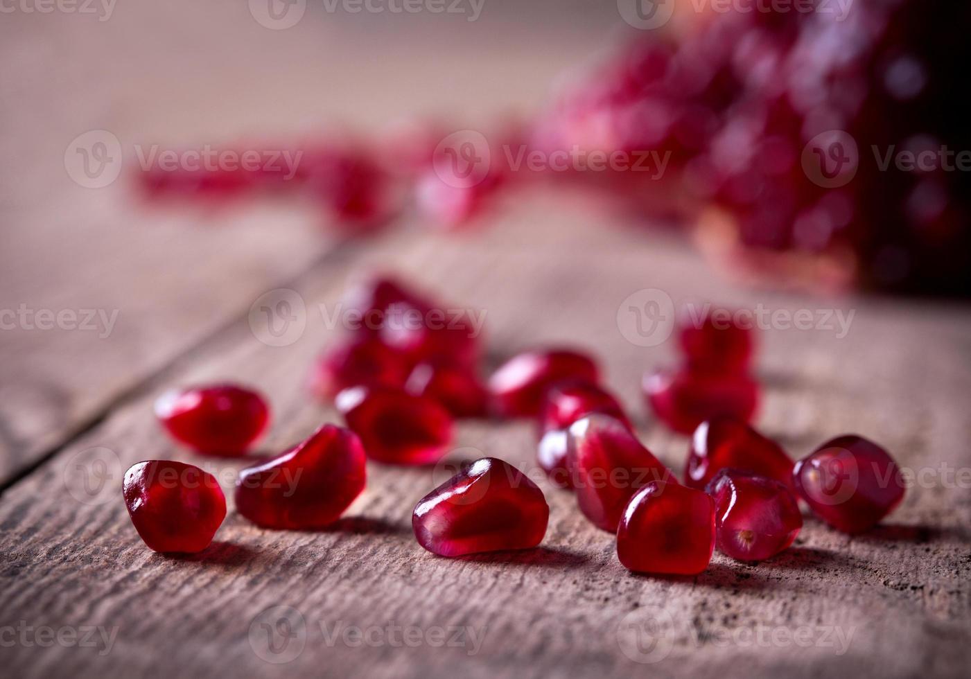 semillas de granada roja en la mesa de madera vieja foto