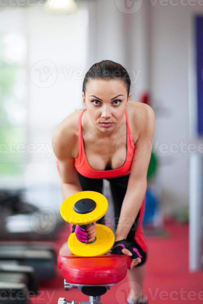 Mujer en el deporte de gimnasio haciendo ejercicios con pesas foto