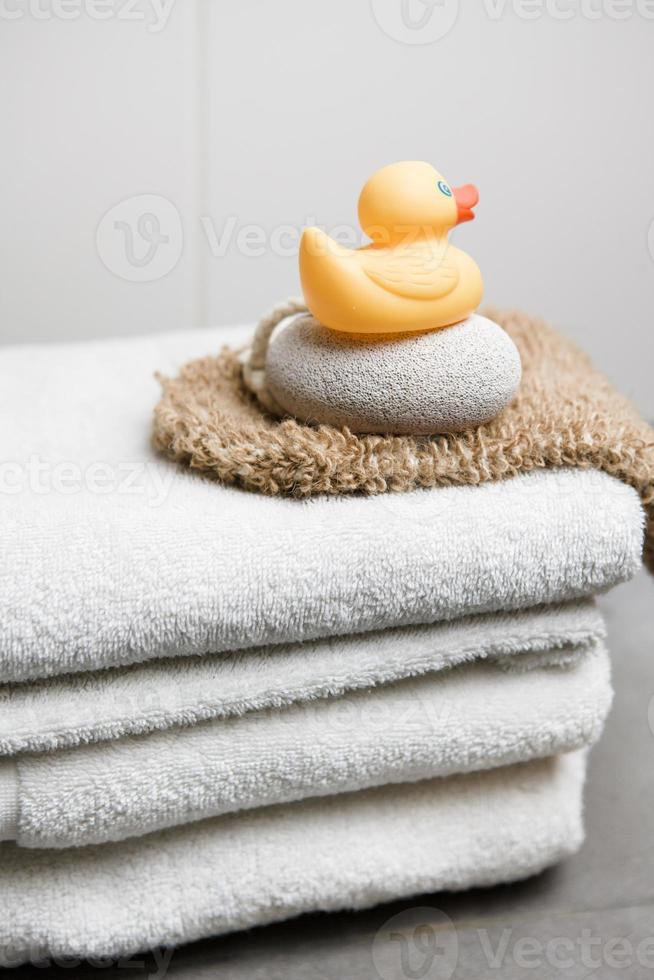 Wellness, white towels pumice stone, peeling glove and rubber duck photo