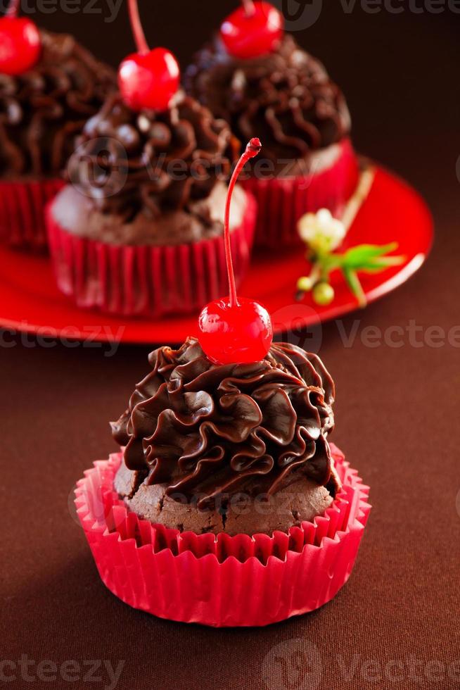 Fresh chocolate muffins with chocolate cream and cherry. photo