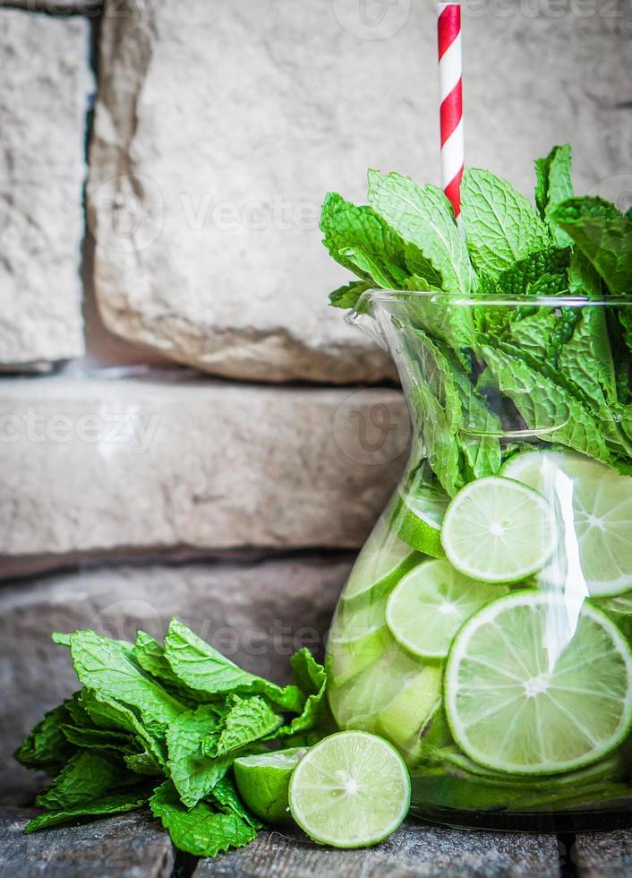 Water with limes and mint on wooden background photo