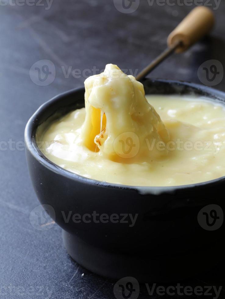 fondue - a piece of bread (croutons) in liquid cheese photo