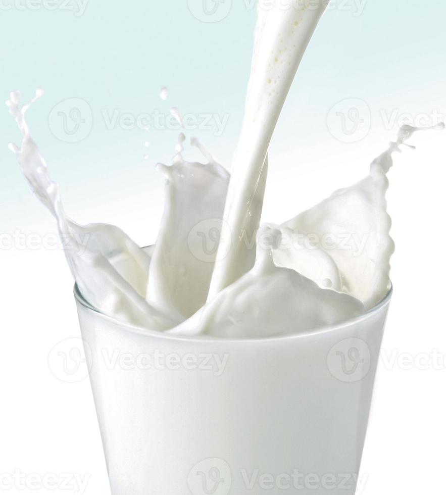 leche fresca que vierte en un vaso con salpicaduras. foto