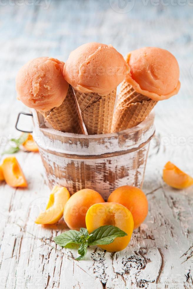 Apricot fresh ice cream scoops in cones on wood photo