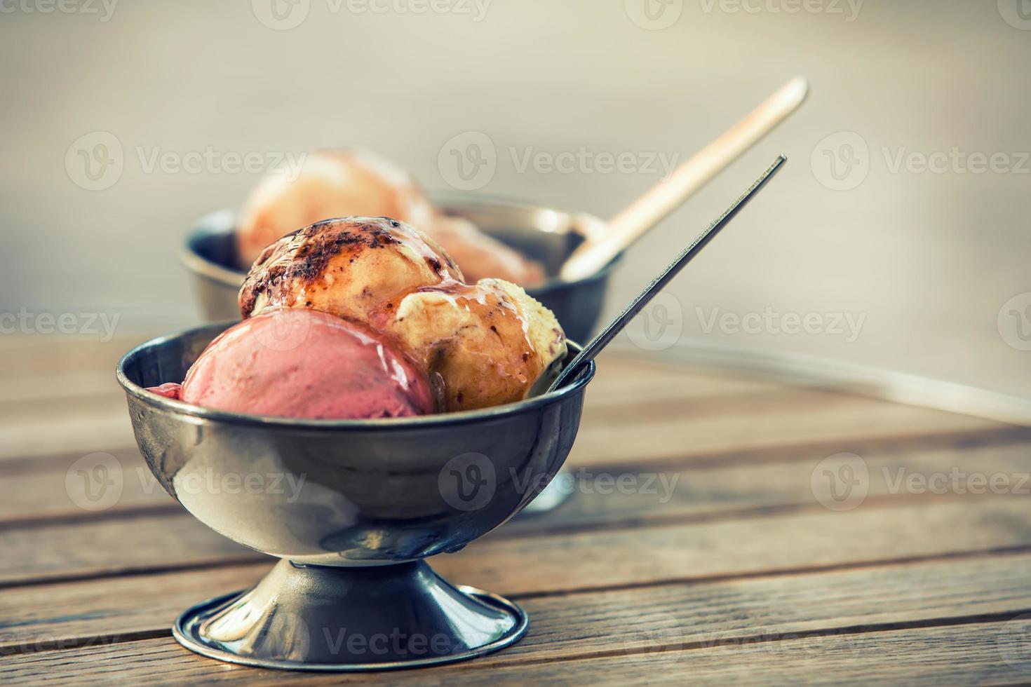 Ice cream in two metal bowls on a wooden table photo