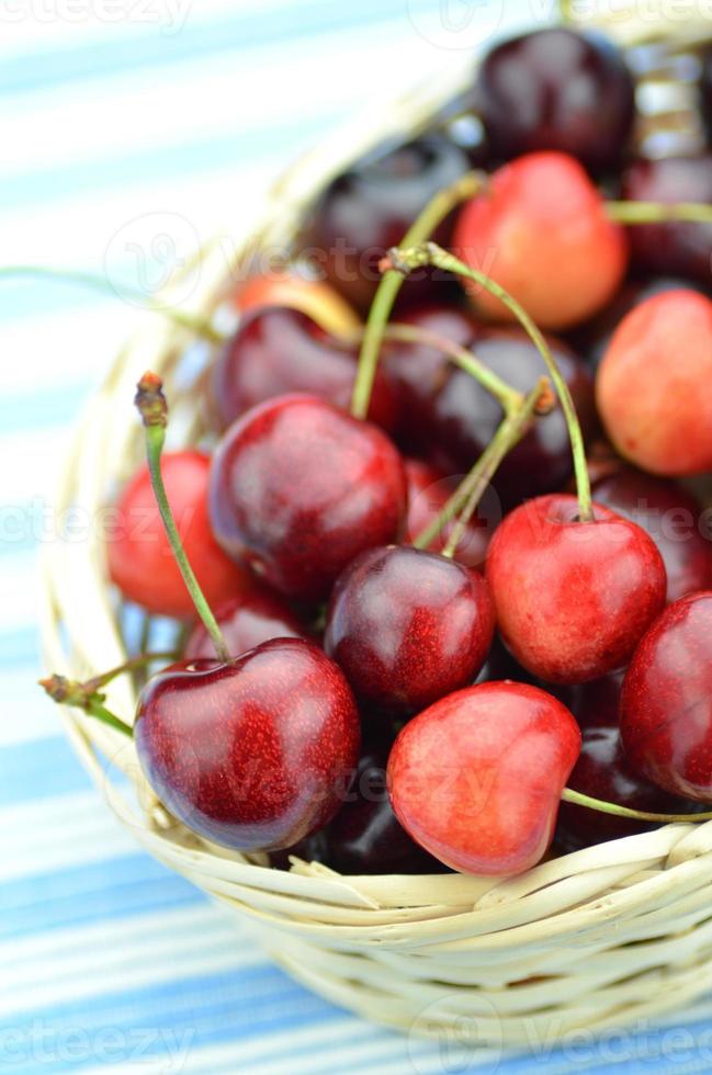 Primer plano de cerezas frescas y dulces maduras en cesta de mimbre foto