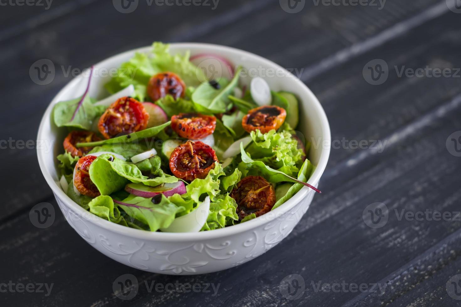 Ensalada con verduras frescas, hierbas de jardín y tomates secados al sol. foto