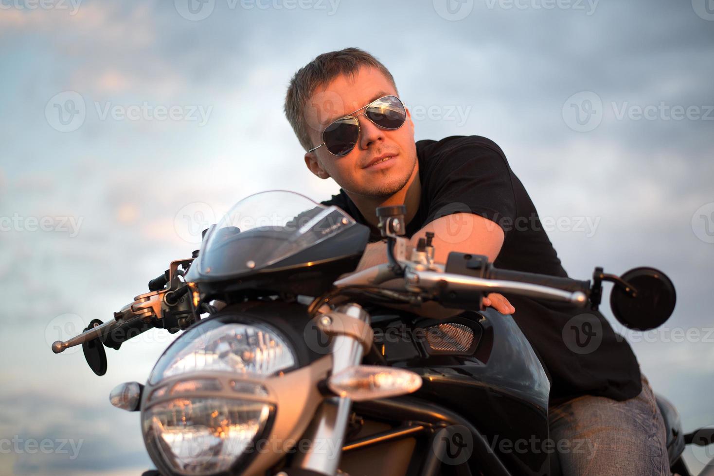 Romantic portrait handsome biker man sits on a bike photo
