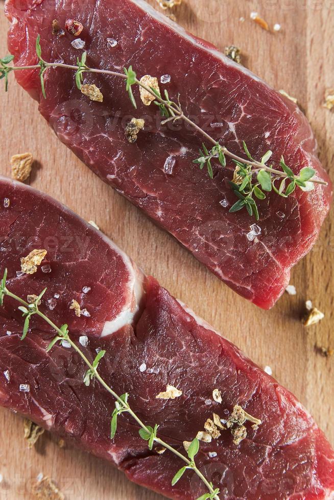 Raw beef tenderloin with spices over wooden table photo