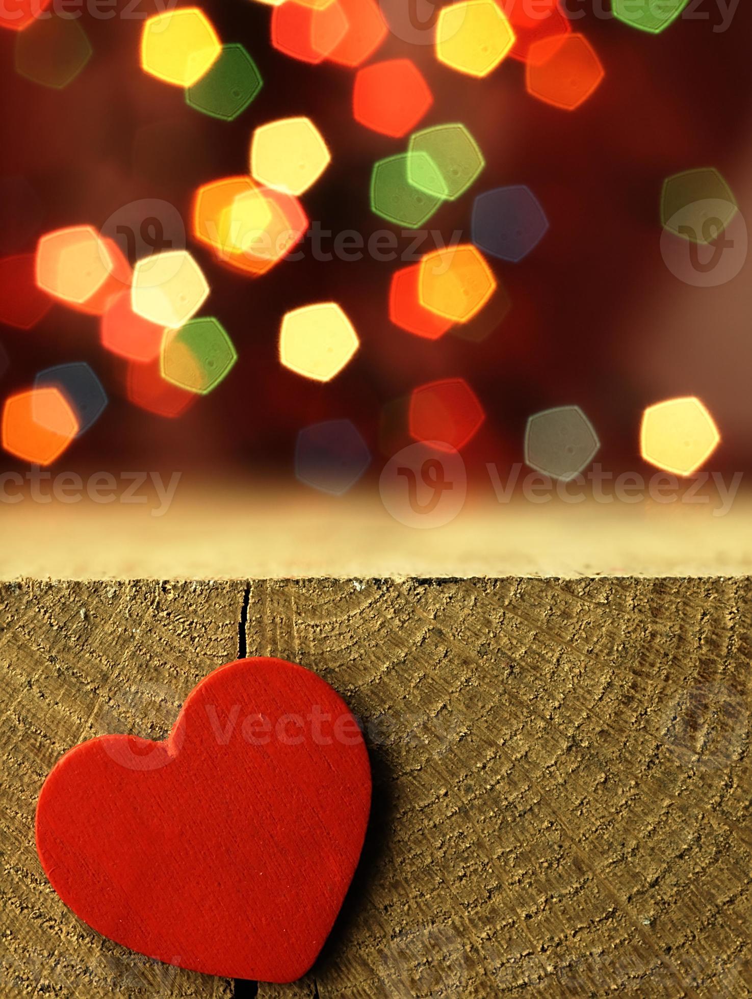 Corazón rojo en el borde de una mesa de madera. foto
