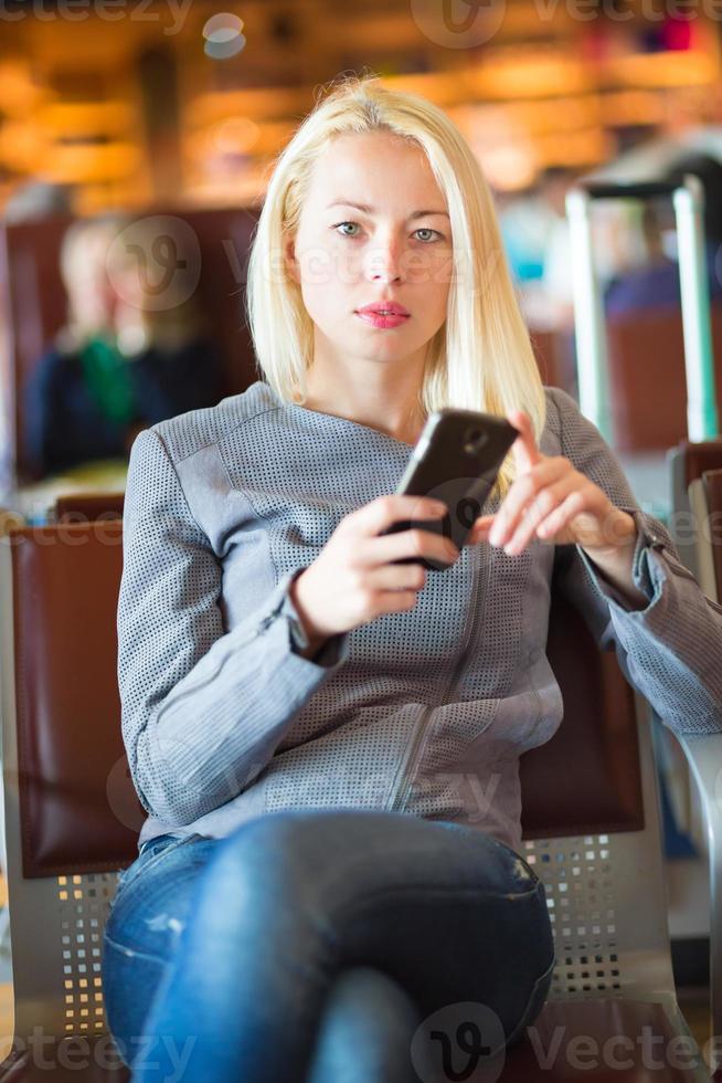 Female traveler using cell phone while waiting. photo