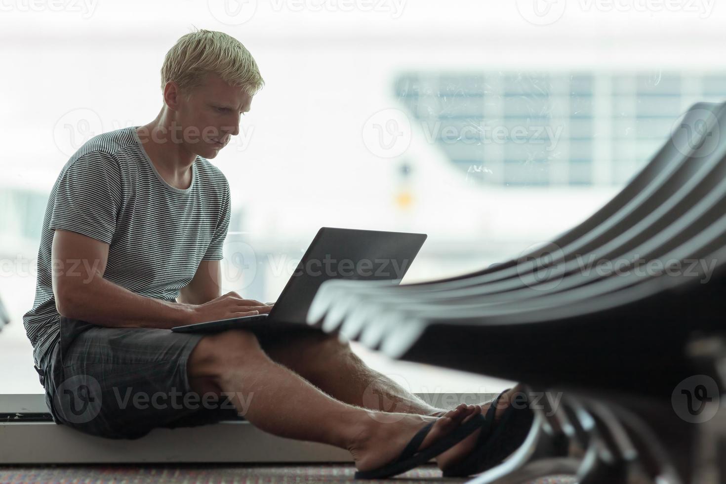 Young man using laptop in airport photo