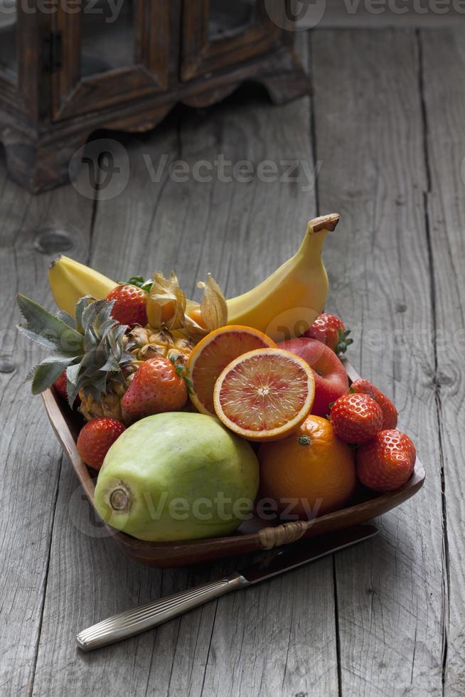 frutero con frutas, cuchillo en madera foto