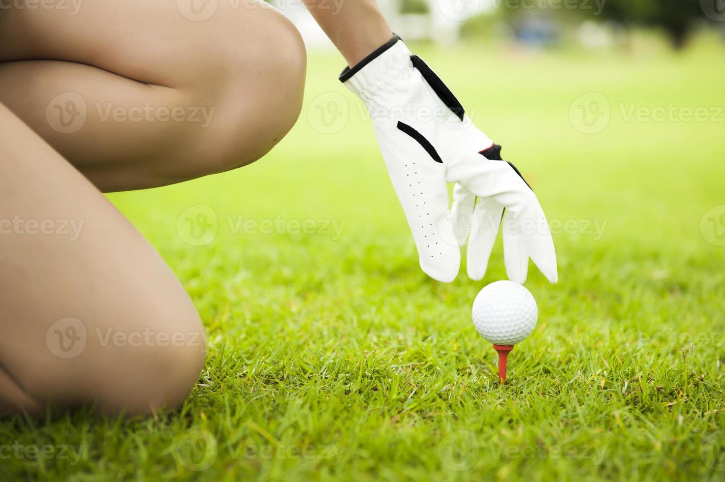 Señora mano colocando la pelota de golf en tee foto