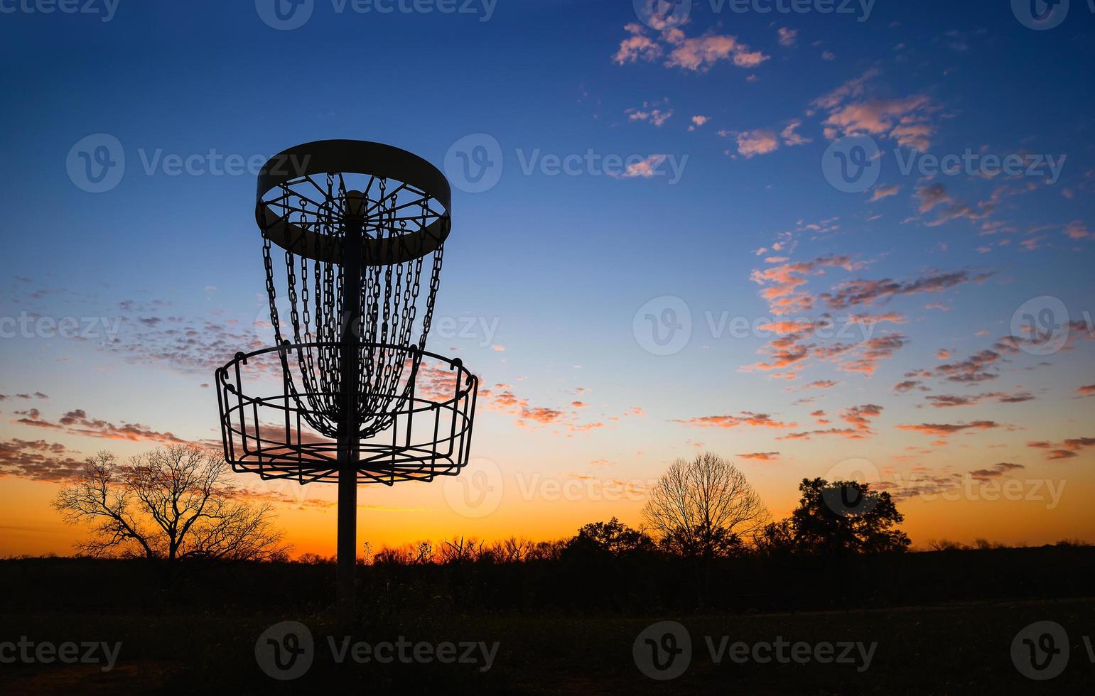 silueta de canasta de golf de disco contra la puesta de sol foto
